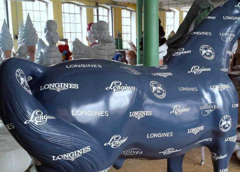 Longines Advertising Object 2 Niebieska rzeźba konia pokryta logo marki Longines w hali produkcyjnej.