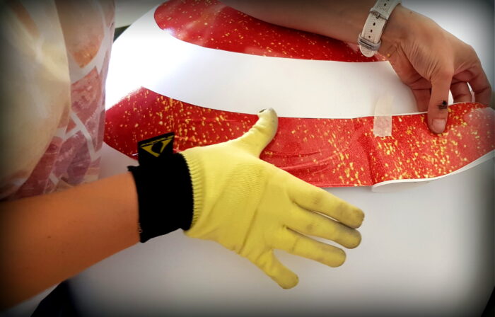 Applying a decorative red and white adhesive film with a gloved hand.