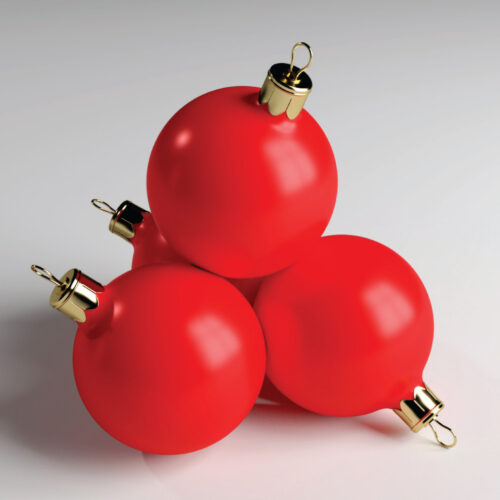Red Christmas baubles with gold caps stacked on a white surface.