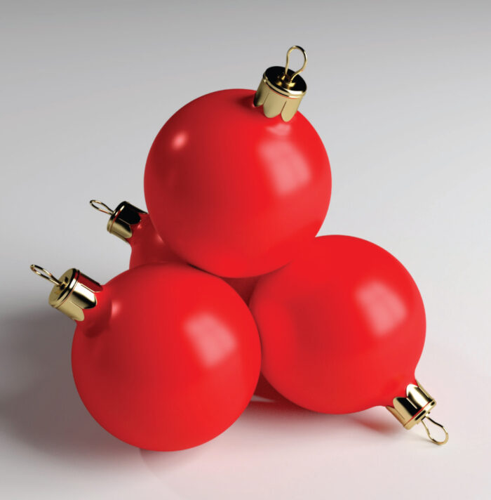 Red Christmas baubles with gold caps stacked on a white surface.