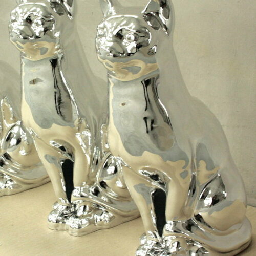 Two shiny, silver-colored cat statues sitting side by side.