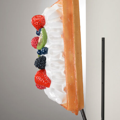 Wall-mounted 3D model of a slice of fruit tart with colorful fruits and whipped cream.