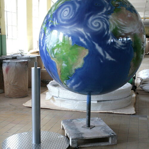 Large painted globe mounted on a stand in a workshop.