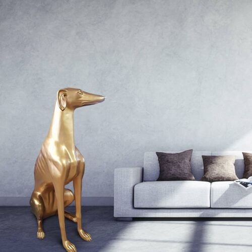 A large golden dog statue next to a modern gray sofa with brown pillows in a minimalist living room.