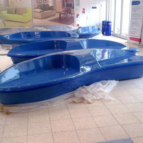 Blue, canoe-shaped benches installed indoors on a tiled floor.