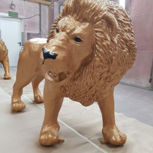 A gold-painted lion sculpture in a workshop.