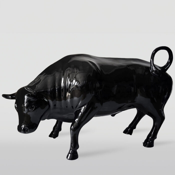 Glossy black sculpture of a bull in a charging stance with a ring in its tail.