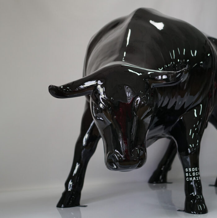 Glossy black sculpture of a bull with "3 DEF BLOCK CHAIR" written on its left front leg.