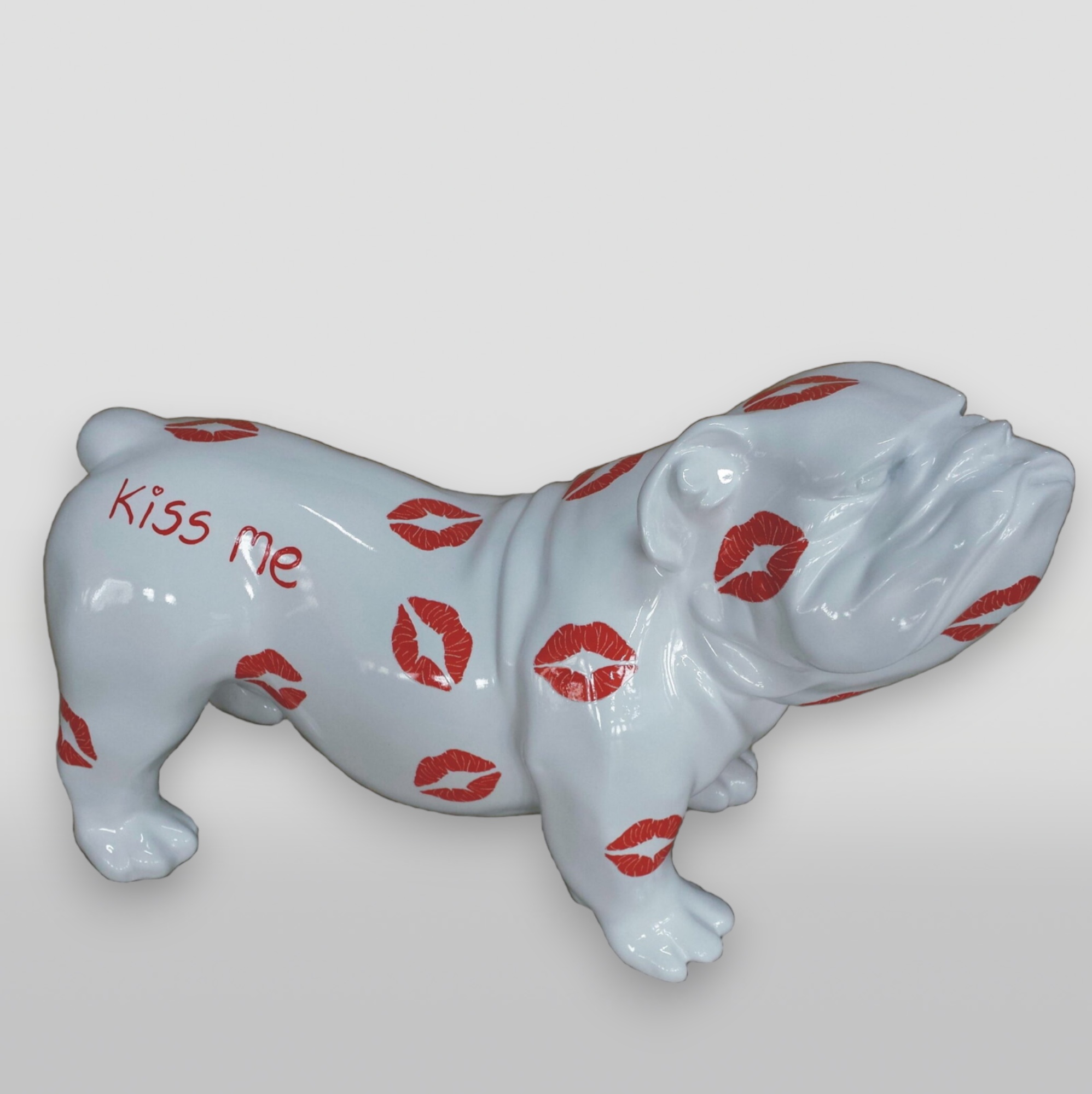 White bulldog statue covered in red lipstick kiss marks and the words