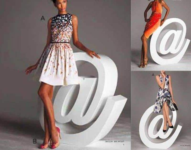 oryg_064490685_1129949550544944_1465385417682452480_o Three women posing with large white "@" symbols, wearing different stylish dresses in varying poses.