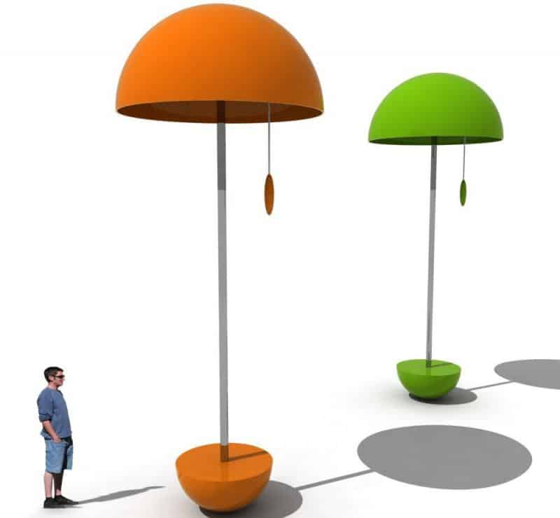 Festival Lamps 3 Dwie duże, nowoczesne lampy z pomarańczowym i zielonym abażurem, obok nich stoi człowiek.