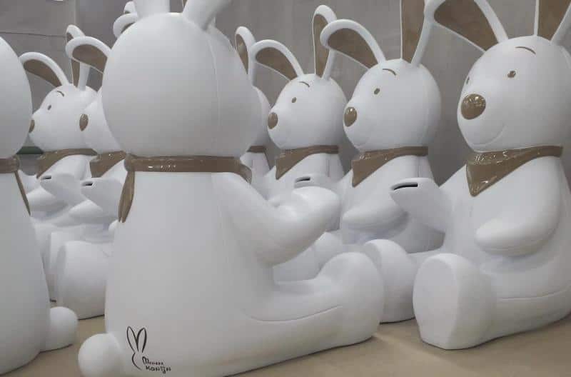 Rabbit Piggy Bank 3 Białe figurki królików z brązowymi detalami siedzące w rzędach.