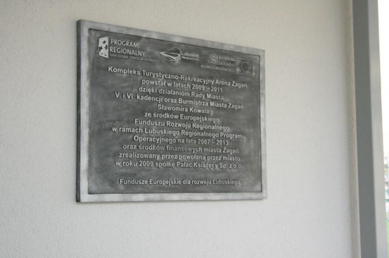 Tablica informacyjna o budowie Kompleksu Turystyczno-Rekreacyjnego Arena Żagań, powstałego w latach 2009-2011 dzięki środkom z Europejskiego Funduszu Rozwoju Regionalnego w ramach Lubuskiego Regionalnego Programu Operacyjnego.