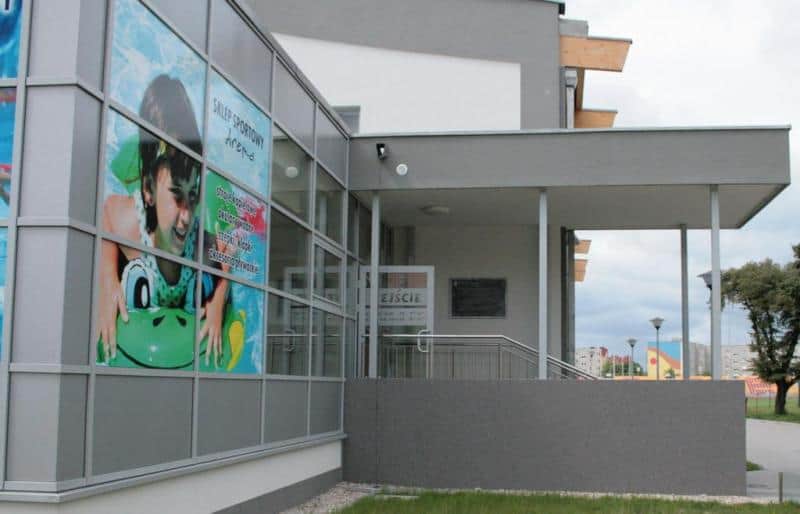 Budynek z dużym plakatem przedstawiającym dziecko na dmuchanym materacu oraz wejściem z napisem 