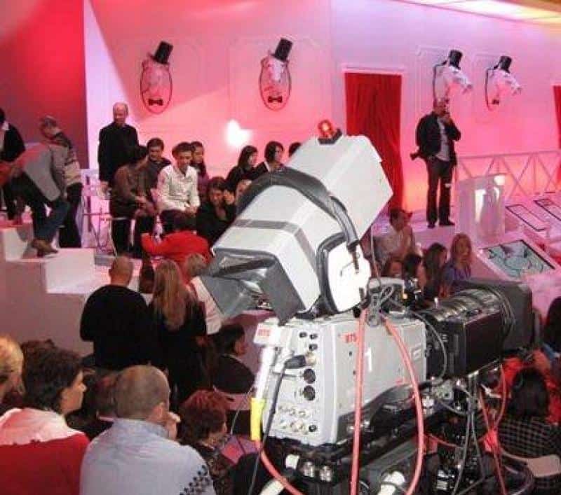 TVP2 - Set Design Elements 3 Nagranie telewizyjne w studio z widownią i dużą kamerą na pierwszym planie. Dekoracje w czerwono-białej kolorystyce.