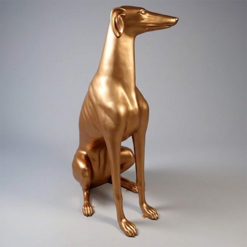 Person leaning against a large gold dog statue in a room with pink walls and decorative molding.