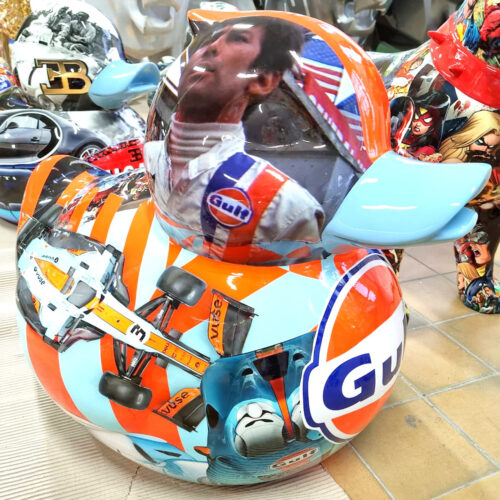 A rubber duck painted with a racing theme, featuring images of a racecar driver with a