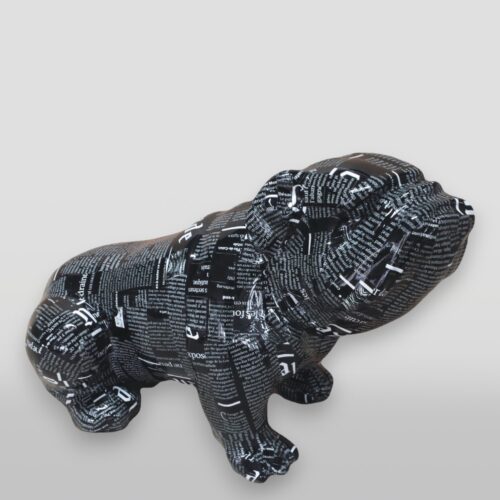 Sculpture of a dog covered with a collage of black and white text.