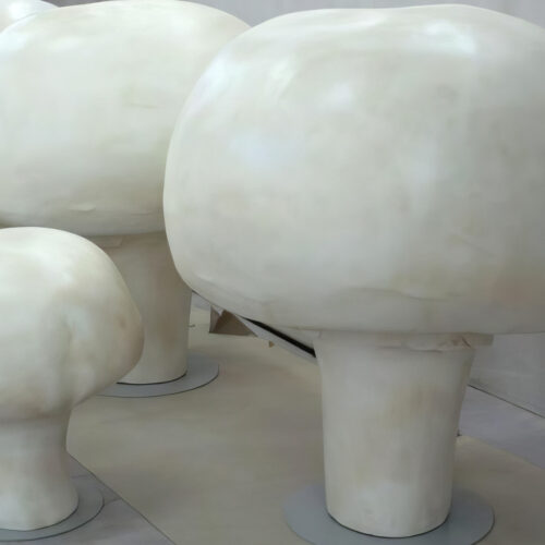Large white mushroom sculptures on a light-colored surface.