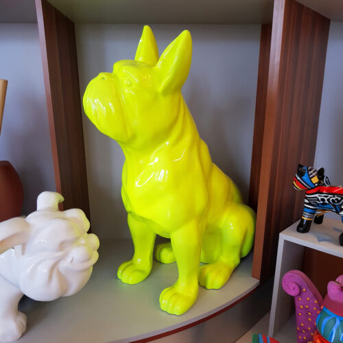 Bright yellow statue of a sitting French Bulldog displayed on a shelf among other colorful sculptures.