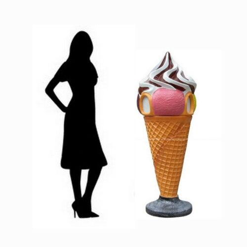 Silhouette of a woman standing next to a large ice cream cone sculpture.