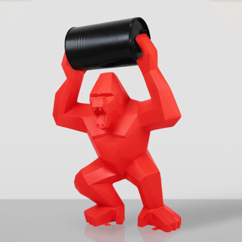 Red geometric gorilla sculpture holding a black barrel above its head on a reflective surface with a light gray background