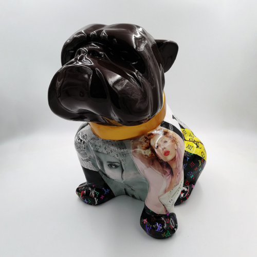A glossy black bulldog statue with a gold collar, featuring collage-style magazine images and colorful patterns on its body.