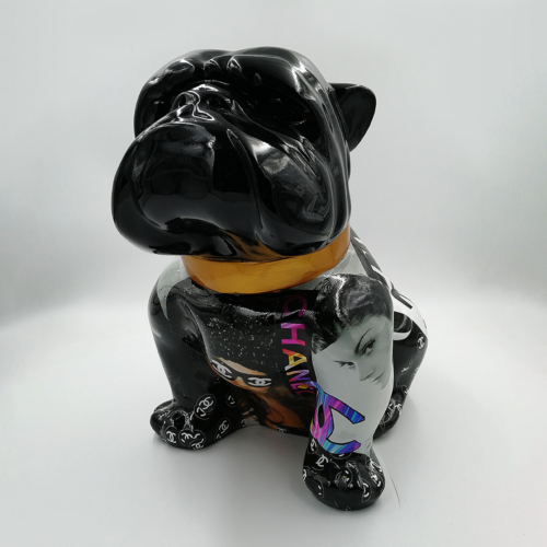 A black ceramic bulldog sculpture with a golden collar and colorful, mixed media designs on its body featuring various images and text.