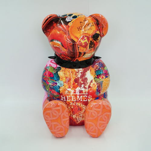 Colorful bear-shaped sculpture with Hermès Paris logo, featuring a mix of abstract and floral patterns, and a skull design on its head.