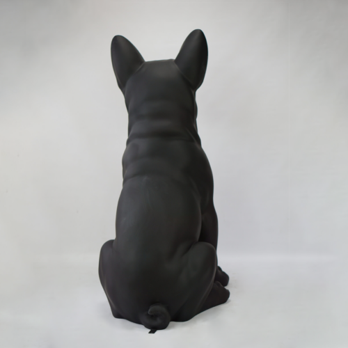 A sculpture of a black dog with its back facing the camera against a white background.