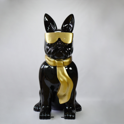 Black dog statue with golden sunglasses and a golden scarf.