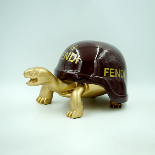 Golden turtle figurine with a brown shell featuring the brand name
