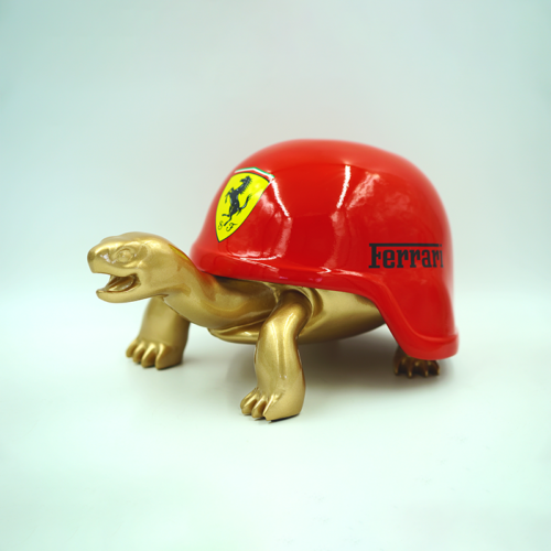Golden tortoise figure wearing a red shell with a Ferrari logo.
