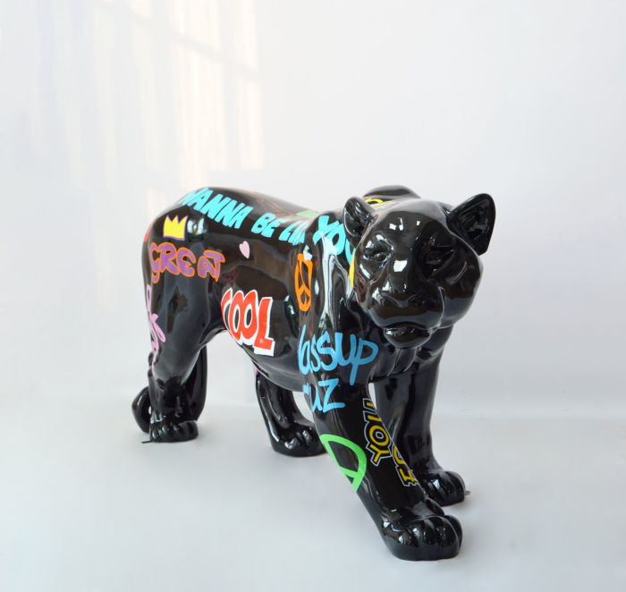 Black ceramic sculpture of a stylized cat with colorful graffiti-style text and symbols.