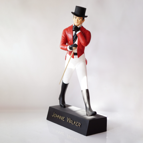A statue of a figure in a top hat, red coat, white pants, and black boots, labeled