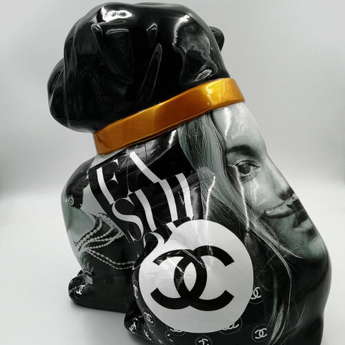 Black dog statue with an orange collar, decorated with images and logos, including a prominent Chanel logo and the text 
