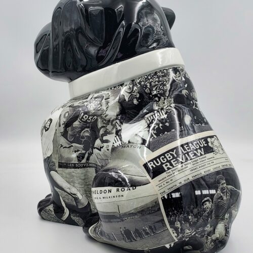 Black ceramic dog statue decorated with vintage newspaper clippings.