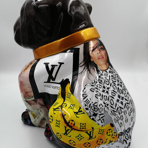 Sculpture of a dog with a dark head and a body covered in various fashion magazine clippings, including images of people and Louis Vuitton branding.