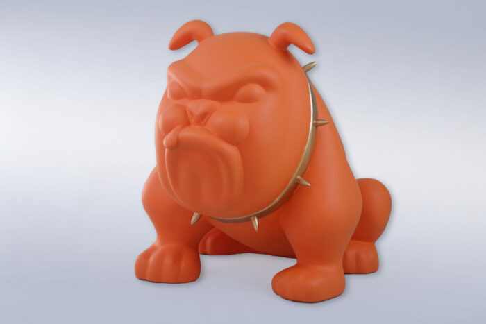 Orange bulldog statue wearing a spiked collar against a plain background.