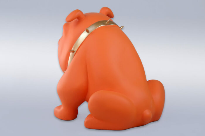 Orange bulldog sculpture with a gold spiked collar, facing away against a neutral background.