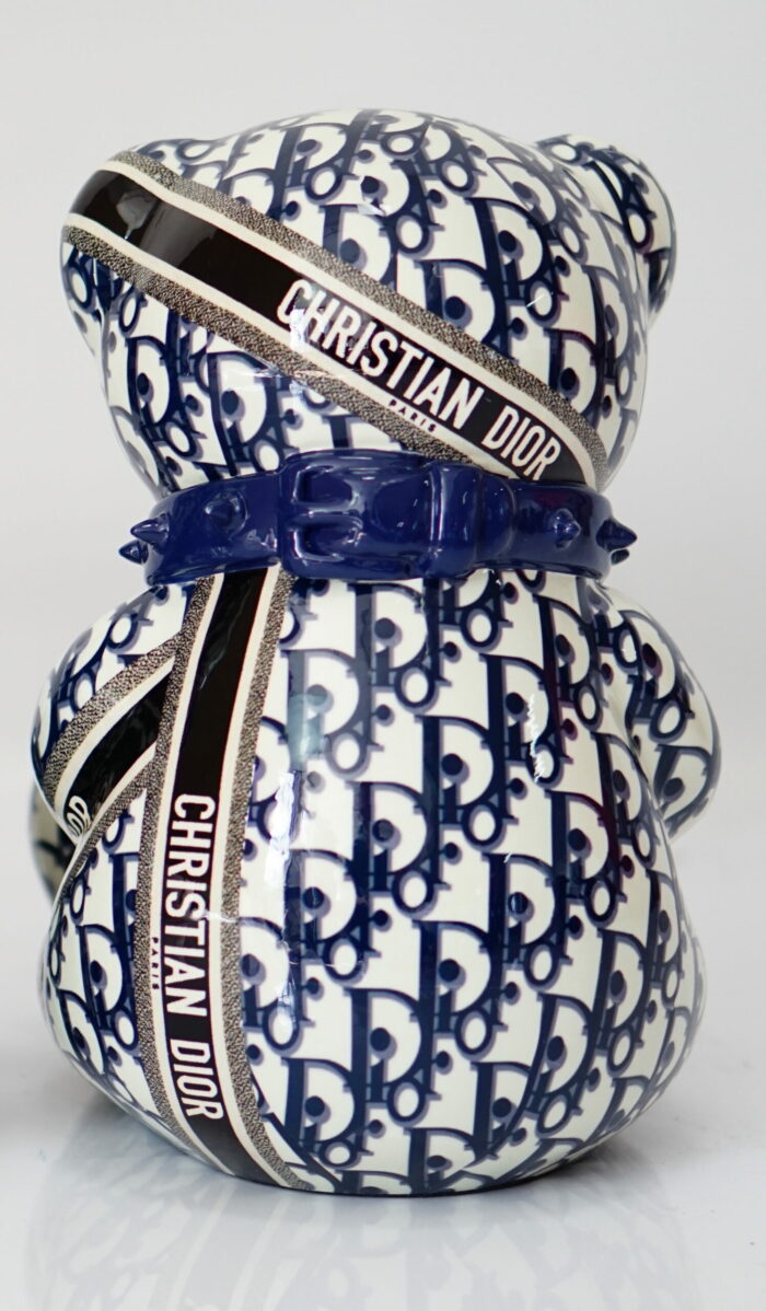 A ceramic teddy bear figurine adorned with a blue and white pattern featuring the Christian Dior logo and multiple "Christian Dior" and "Paris" text bands.