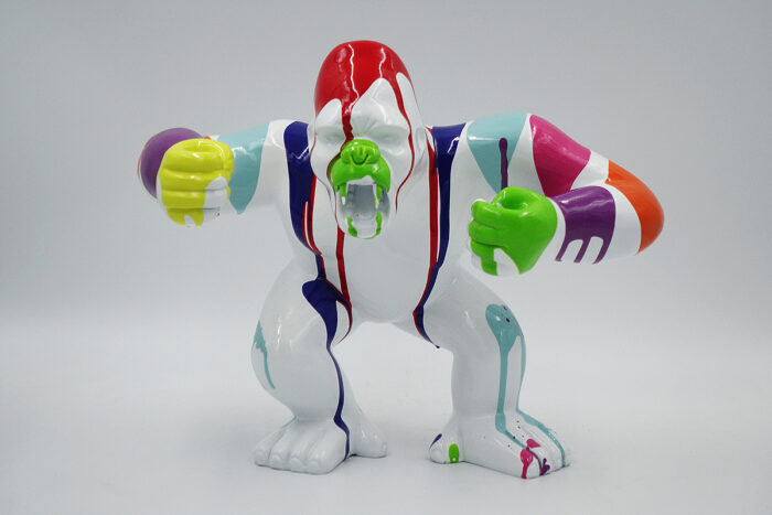 A colorful sculpture of a gorilla with paint drips in various hues, including green, red, blue, purple, yellow, and orange, standing against a plain background.