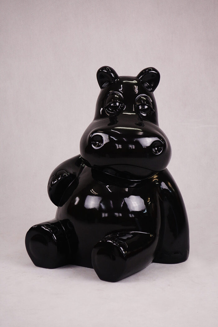 Glossy black sculpture of a cartoonish hippopotamus sitting down.