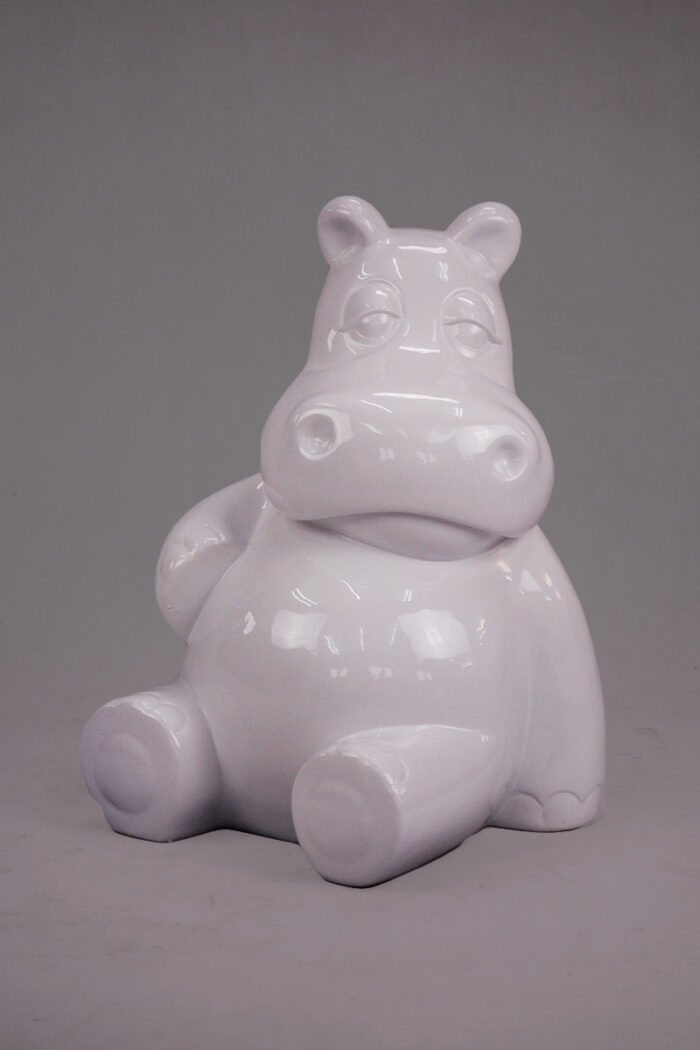 White ceramic figurine of a hippo in a seated position.