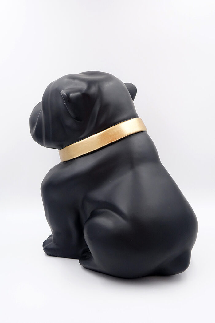 Black bulldog figurine wearing a gold collar, facing away.