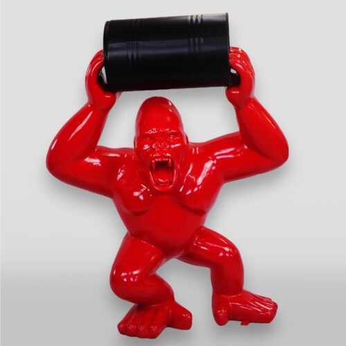 Sculpture of a red gorilla holding a black barrel above its head.