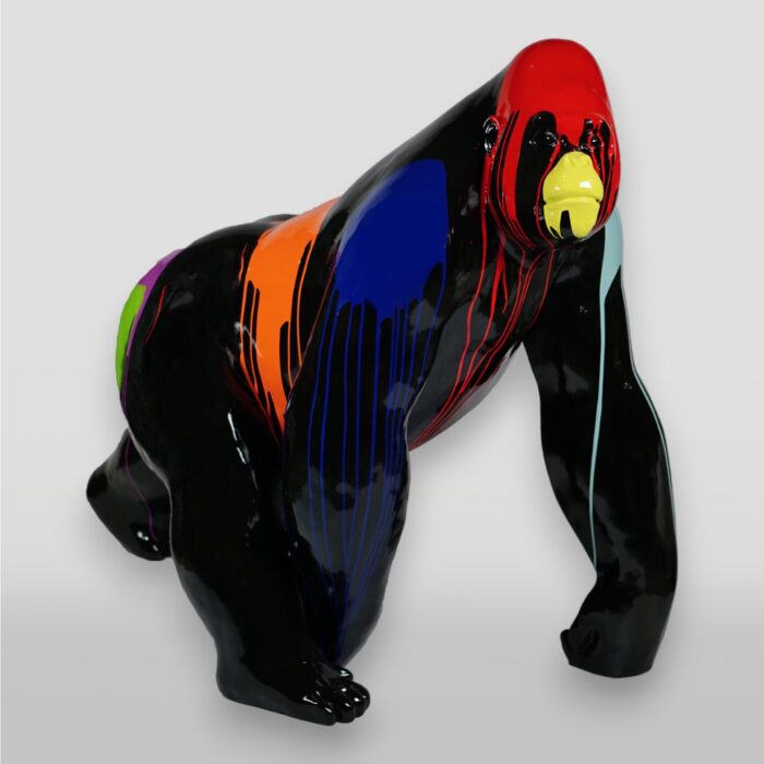 A glossy black gorilla sculpture decorated with vibrant, dripping colors including red, blue, orange, yellow, green, and purple.