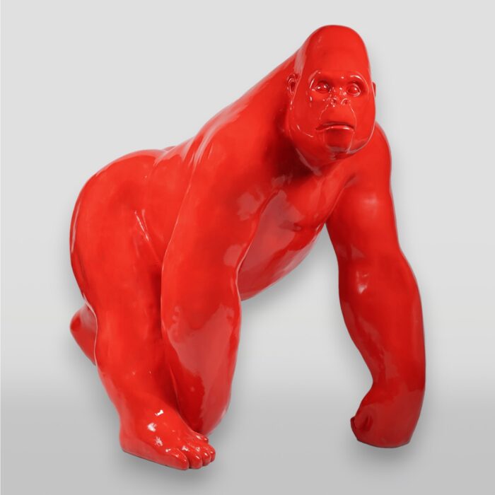 Red gorilla statute on all fours facing the camera against a gray background.