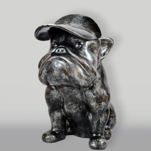 A statue of a bulldog wearing a baseball cap, made of a dark, glossy material.
