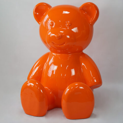 Orange glossy bear sculpture on a light gray background.